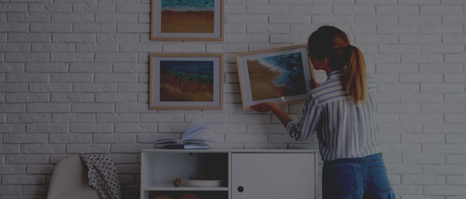 Women arranging picture frames on the wall using brick hooks.