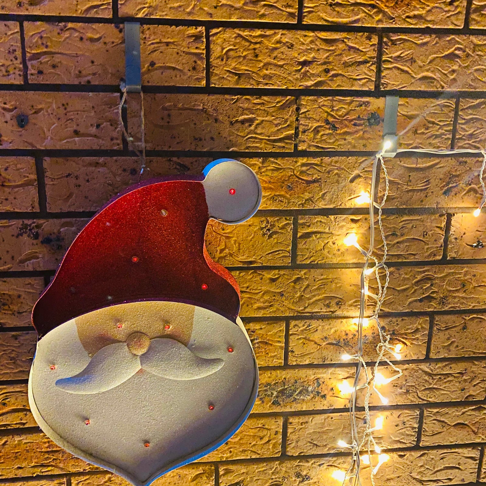 Holiday decorations and fairy lights hung on the brick wall using the Brick Hanger.