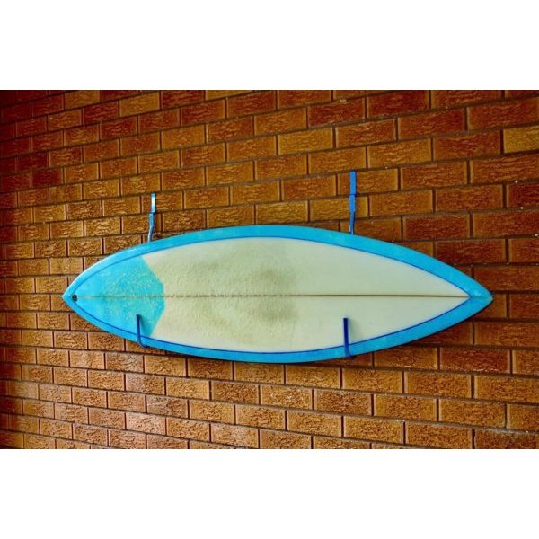 Surfboard hanging on the brick wall with two blue surfboard hangers