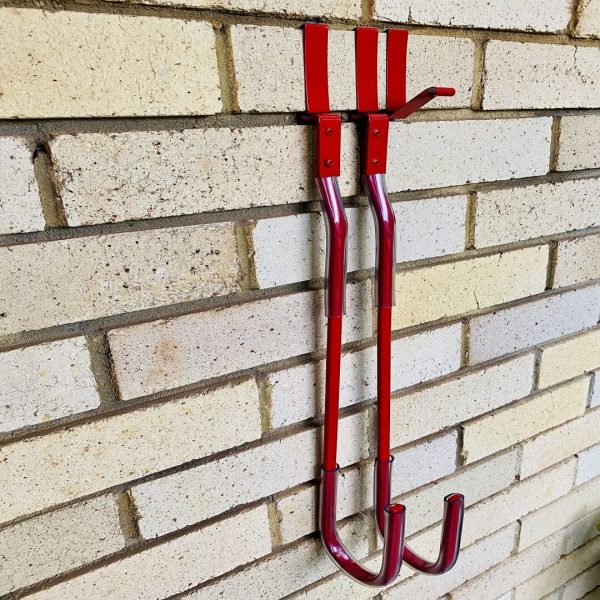 Two red surfboard hangers hanging on the brick wall
